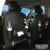 Black PU leather car seat back organiser with multiple pockets and a built-in trash can compartment