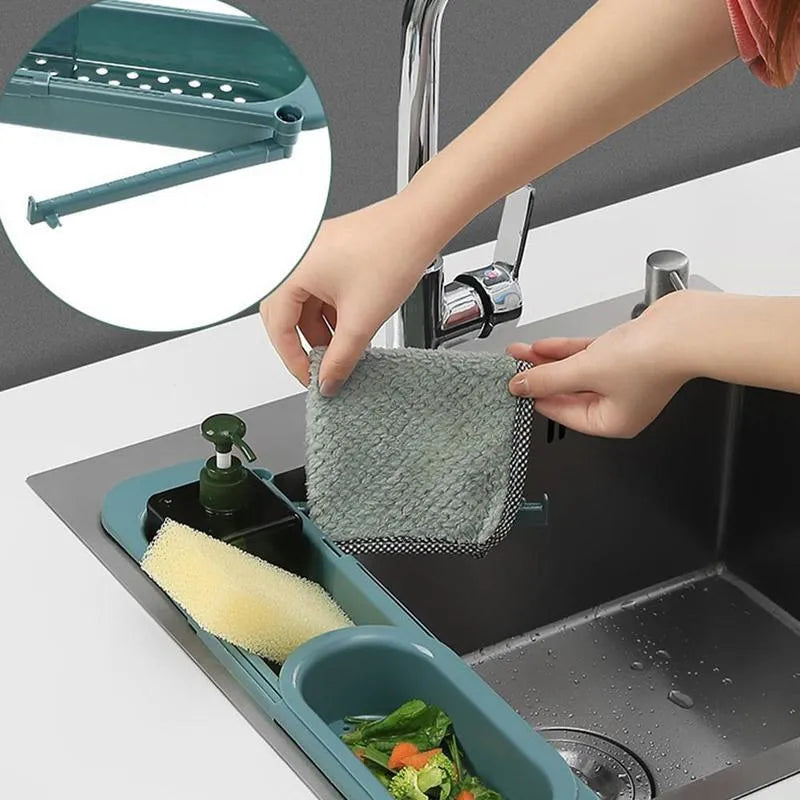 Blue grey adjustable telescopic kitchen sink organiser rack with drainage holes holding a sponge and brush