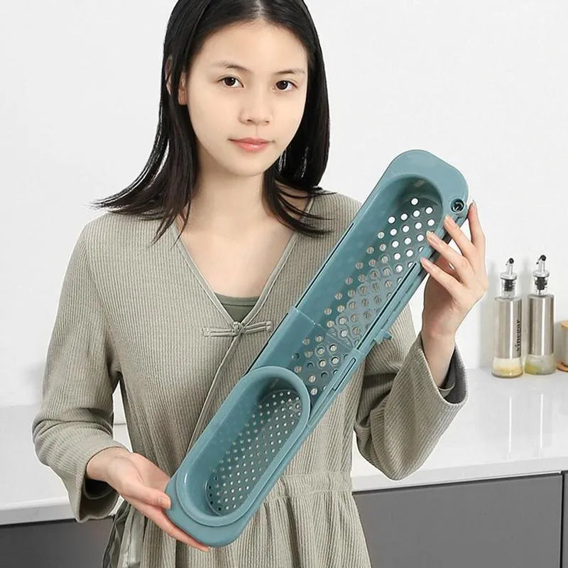 Blue grey adjustable telescopic kitchen sink organiser rack with drainage holes holding a sponge and brush