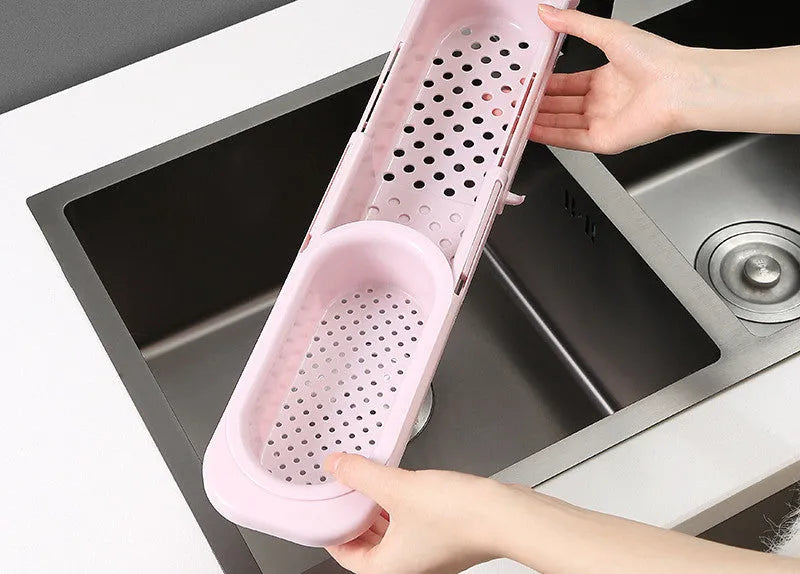 Blue grey adjustable telescopic kitchen sink organiser rack with drainage holes holding a sponge and brush