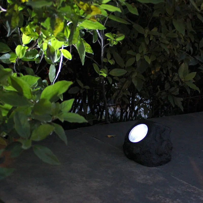 Black solar lamp with simulation stone exterior in outdoor garden setting, IP65 rated LED light
