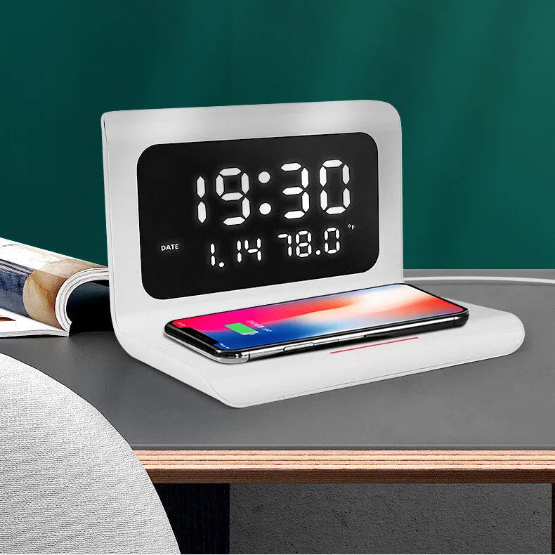 White wireless charging alarm clock showing calendar, temperature display, and phone charging on surface