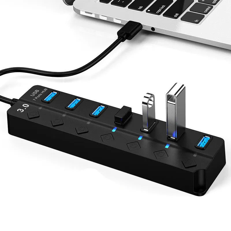 Black 7-port high-speed USB 3.0 hub with external power adapter on a desk.