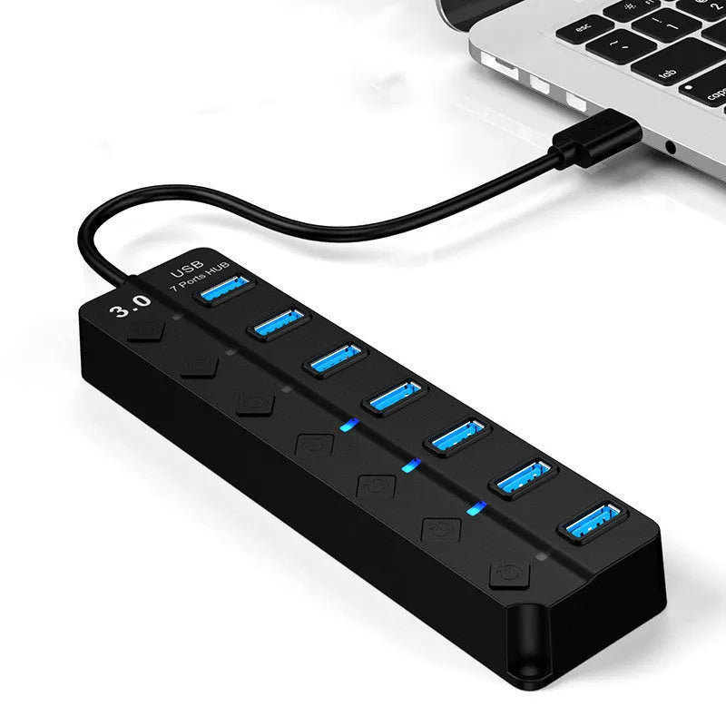Black 7-port high-speed USB 3.0 hub with external power adapter on a desk.