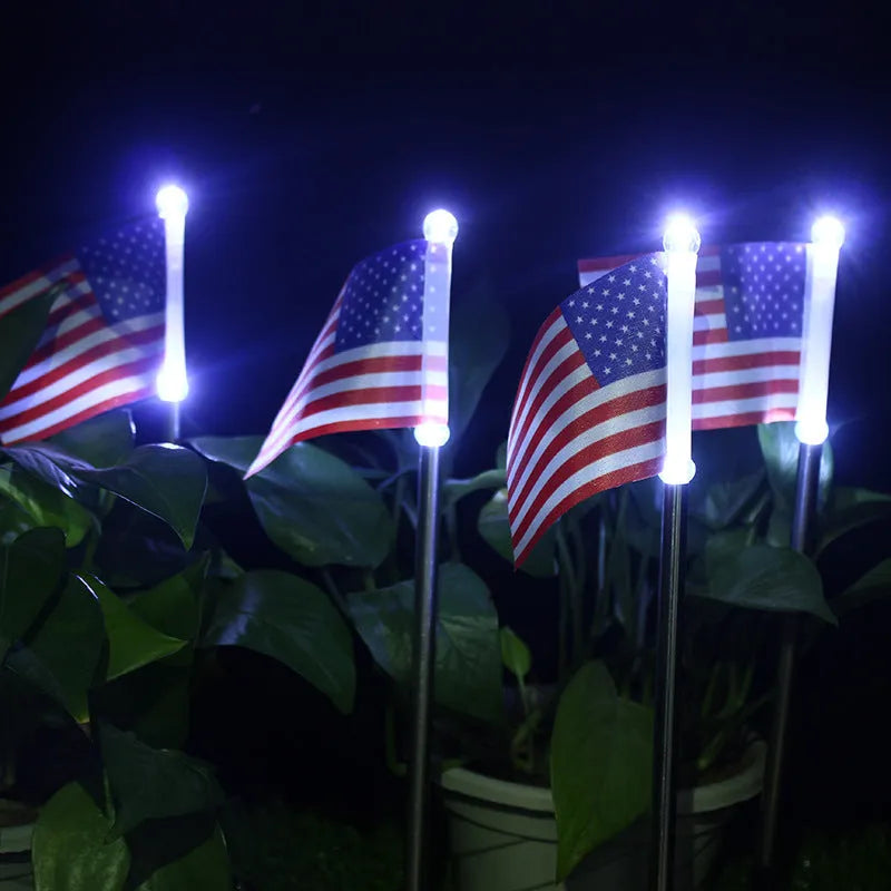 White solar-powered garden flag light showing American flag design on stainless steel pole.