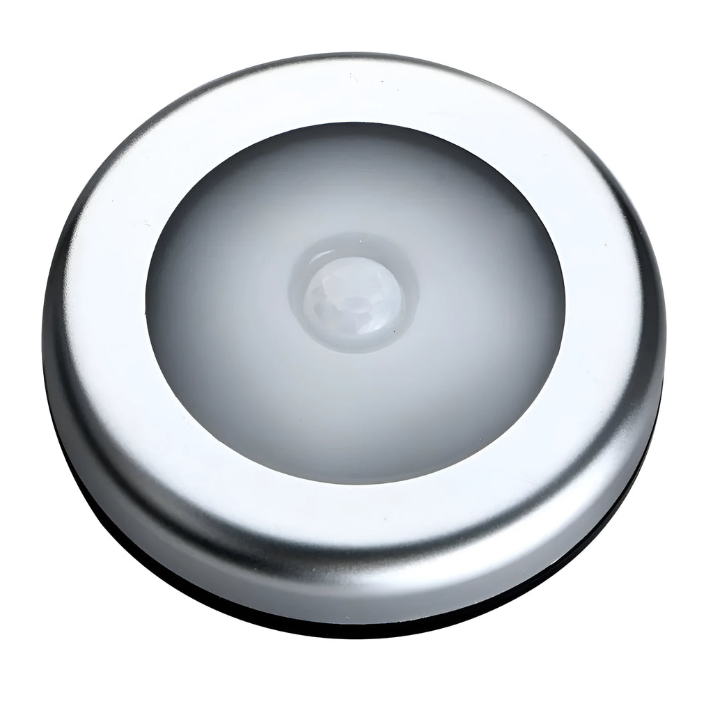 Silver circular battery-powered motion sensor night light on a surface.