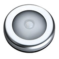 Silver circular battery-powered motion sensor night light on a surface.