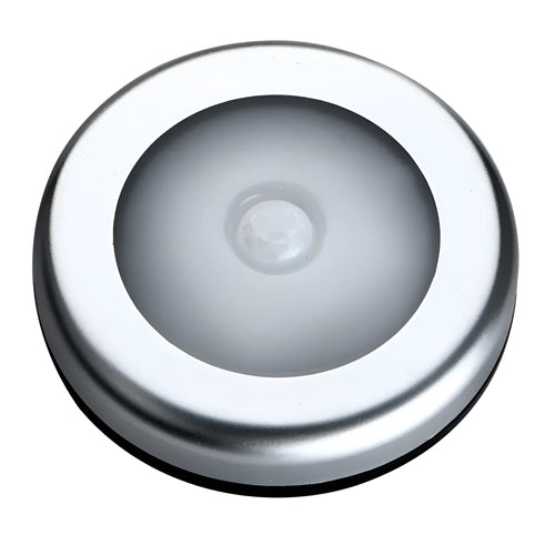 Silver circular battery-powered motion sensor night light on a surface.