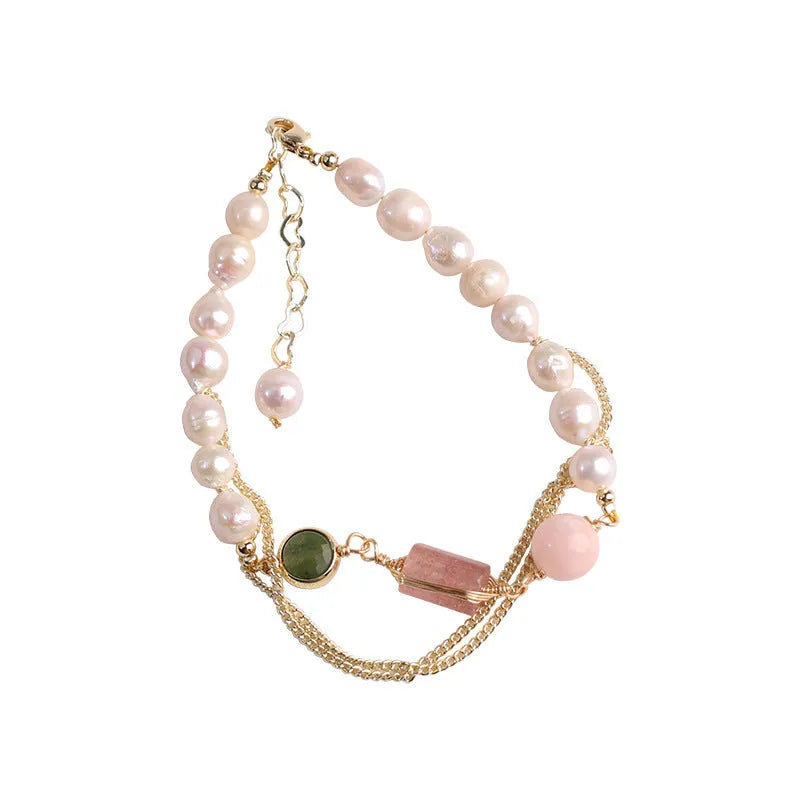 Close-up of a women's bracelet with pink freshwater pearls and geometric strawberry crystal charms on a stainless steel chain.