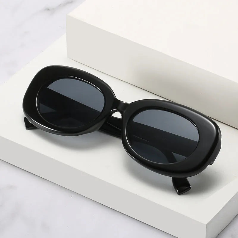 Oval fashion sunglasses for women with black PC frame and UV400 AC lenses