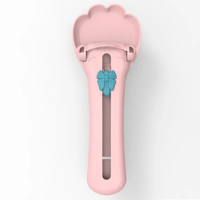 Green and pink pet food squeezer feeder with attached spoon for dispensing liquid and dry food