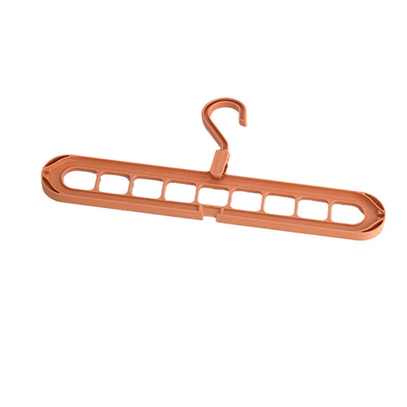 Green plastic folding clothes hanger with nine holes for organising trousers on a rack.