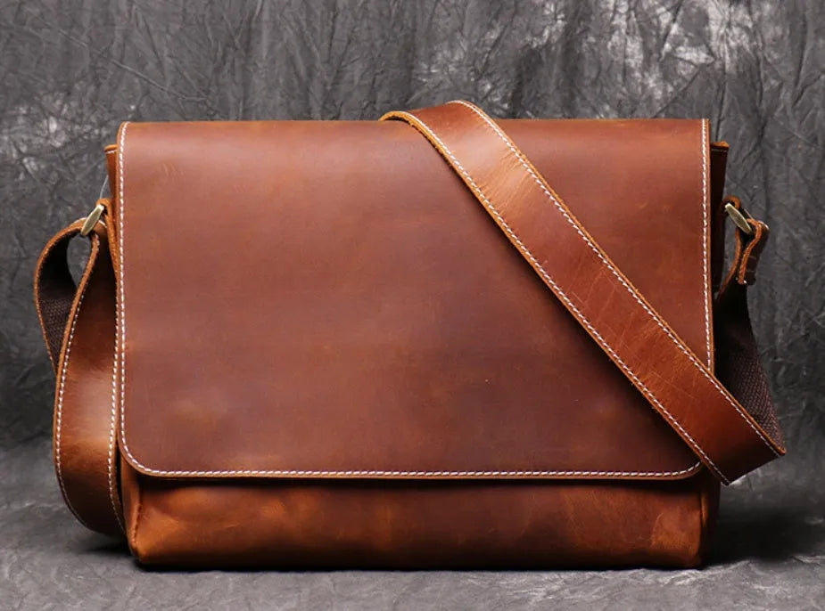 Men's vintage brown cowhide medium messenger bag showing front flap and long shoulder strap.