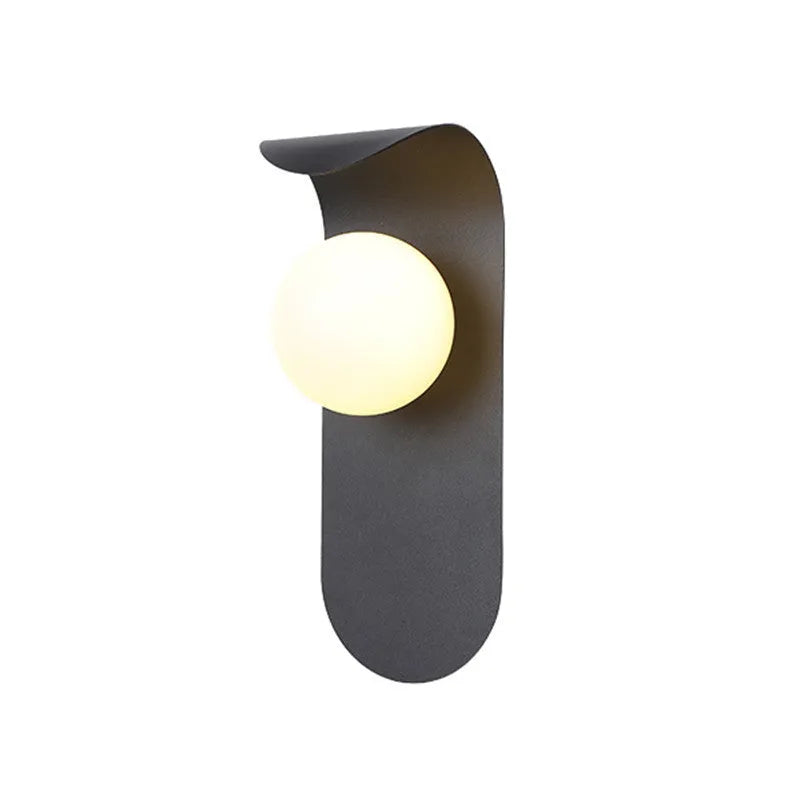 Modern minimalist black wall lamp with iron shade and LED light on a bedroom wall