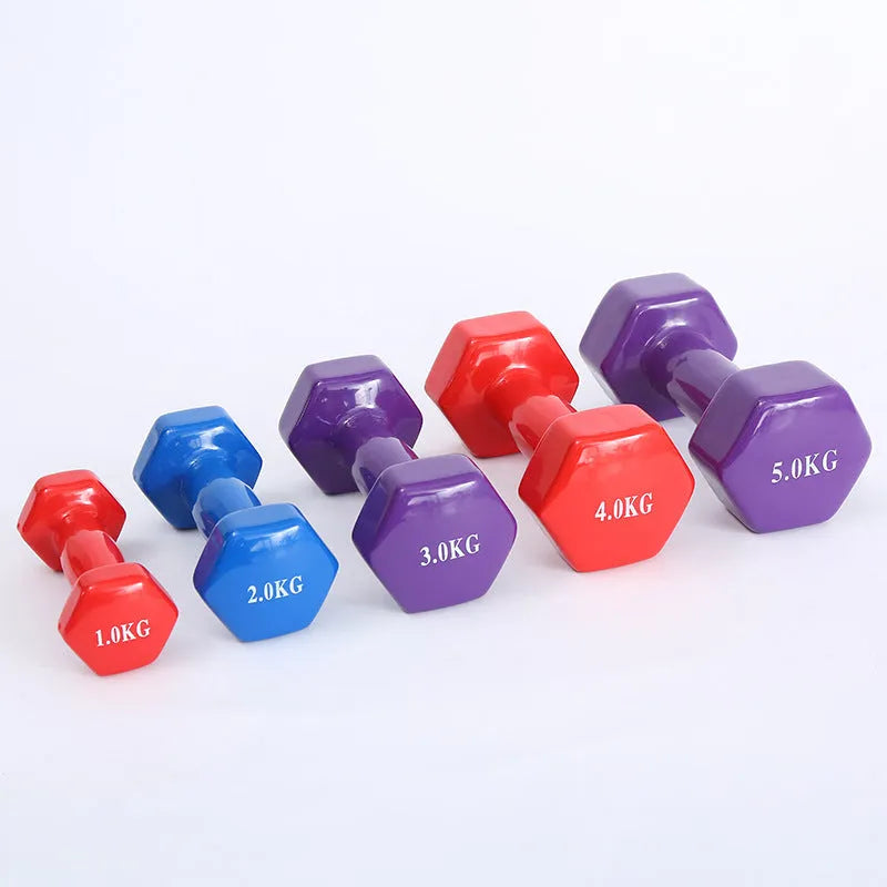 Set of bright colour plastic fitness dumbbells in various weights on a floor.