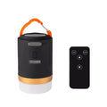 Black rechargeable LED camping light with hanging hook and remote control on a table