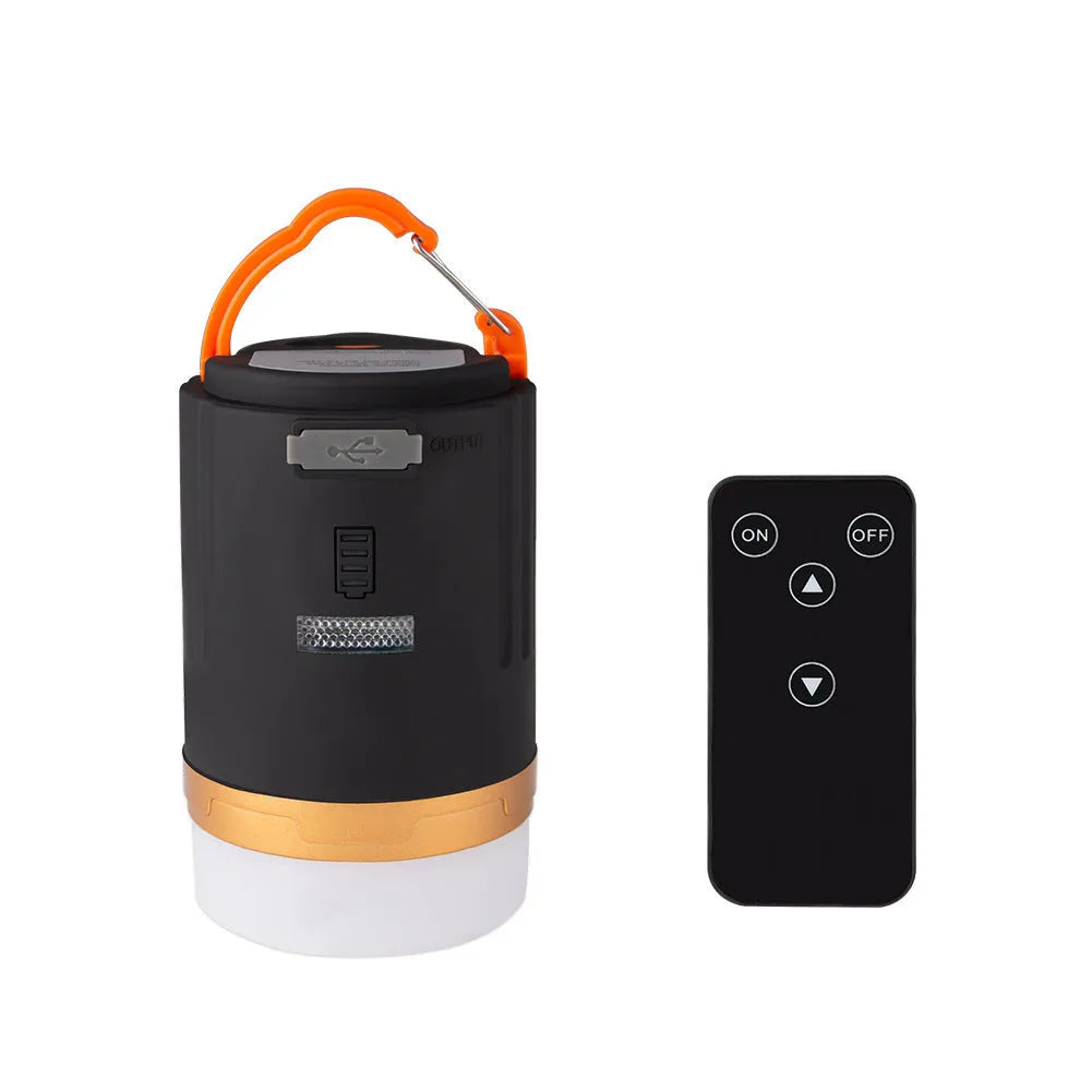 Black rechargeable LED camping light with hanging hook and remote control on a table