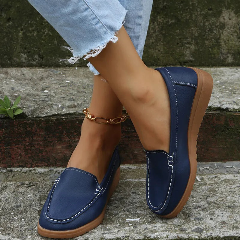 Women's flat slip-on loafers in PU leather with car suture detail, shown in multiple colours.