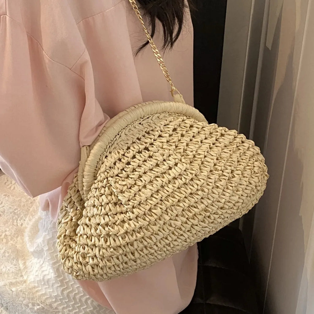 Women's straw beach bag with chain trim in khaki colour, showing shell shape and shoulder strap