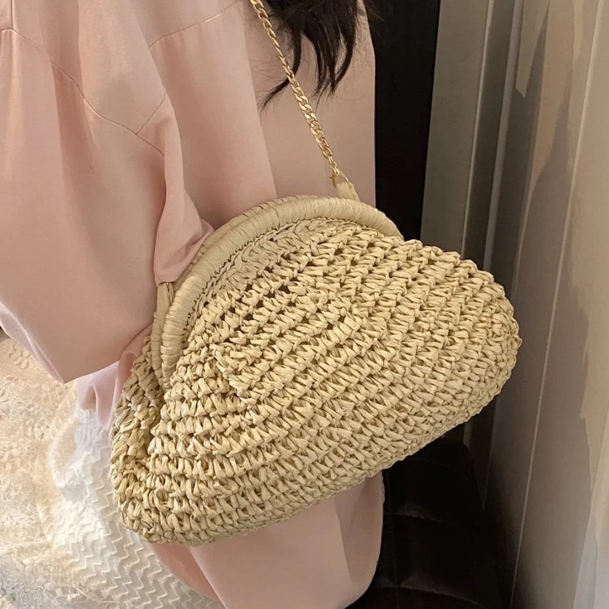 Women's straw beach bag with chain trim in khaki colour, showing shell shape and shoulder strap