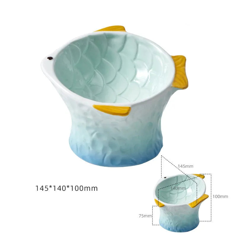 Blue fish-shaped ceramic cat feeder bowl with shallow tilt angle and non-slip base on a wooden surface.
