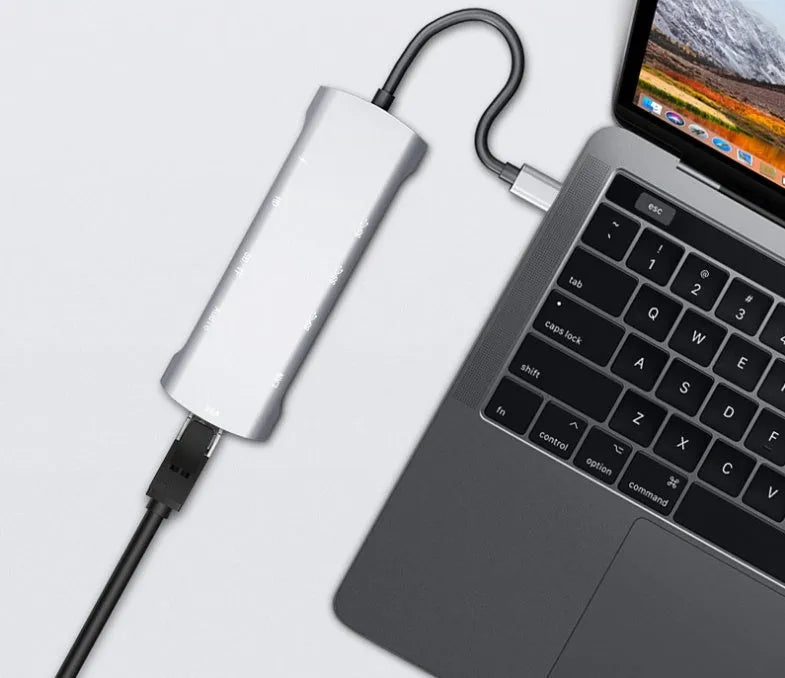 Grey aluminium USB-C docking station with HDMI, VGA, USB ports, and a short cable.