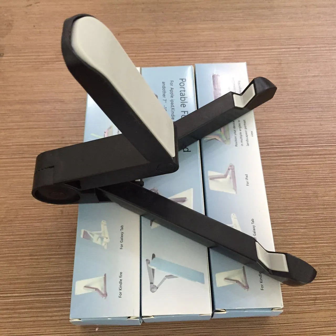 Black foldable tablet holder stand supporting a smartphone in landscape mode on a desk.