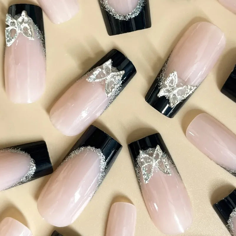 Black French-style false nails with glitter butterfly design on a hand.