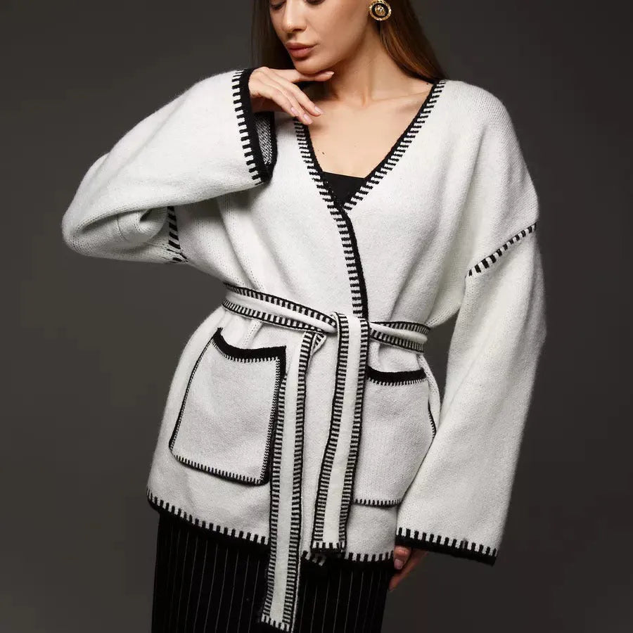 A loose, mid-length knitted cardigan with a front lace-up detail, shown in a camel colour.