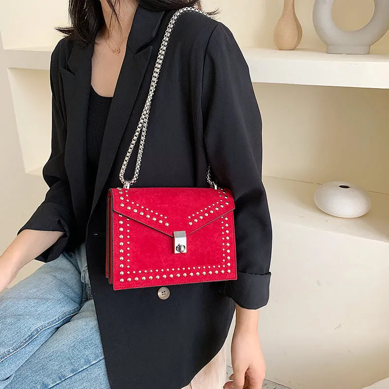 Small PU shoulder messenger bag for women with lock detail, chains, and rivet decoration on a soft flap.