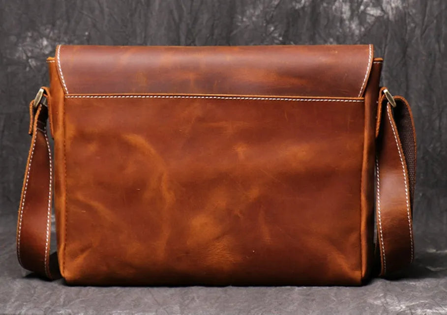 Men's vintage brown cowhide medium messenger bag showing front flap and long shoulder strap.