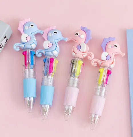 Cute cartoon four-colour press ballpoint pen with silicone grip and 0.7mm tip on a notepad.