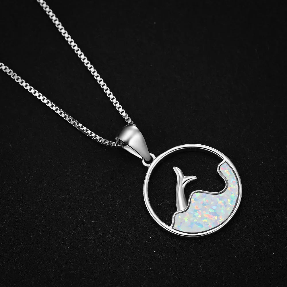 A round geometric fishtail pendant necklace with a white gold electroplated finish, shown in blue opal and white opal colour options.
