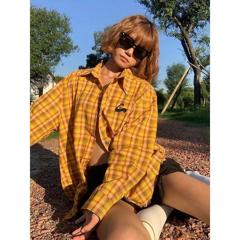 A loose yellow and black plaid shirt with a cardigan style, shown on a hanger.