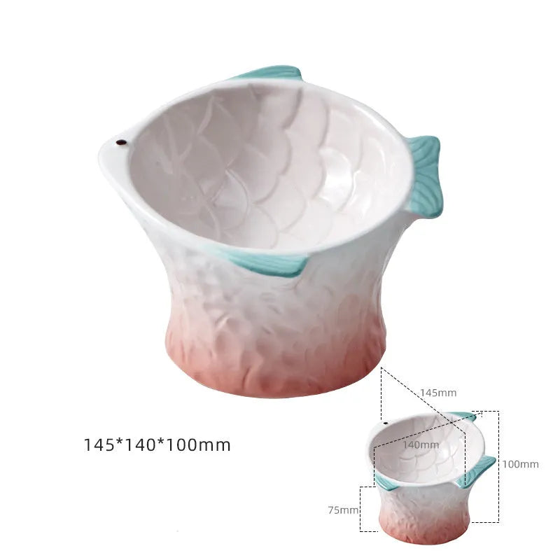 Blue fish-shaped ceramic cat feeder bowl with shallow tilt angle and non-slip base on a wooden surface.