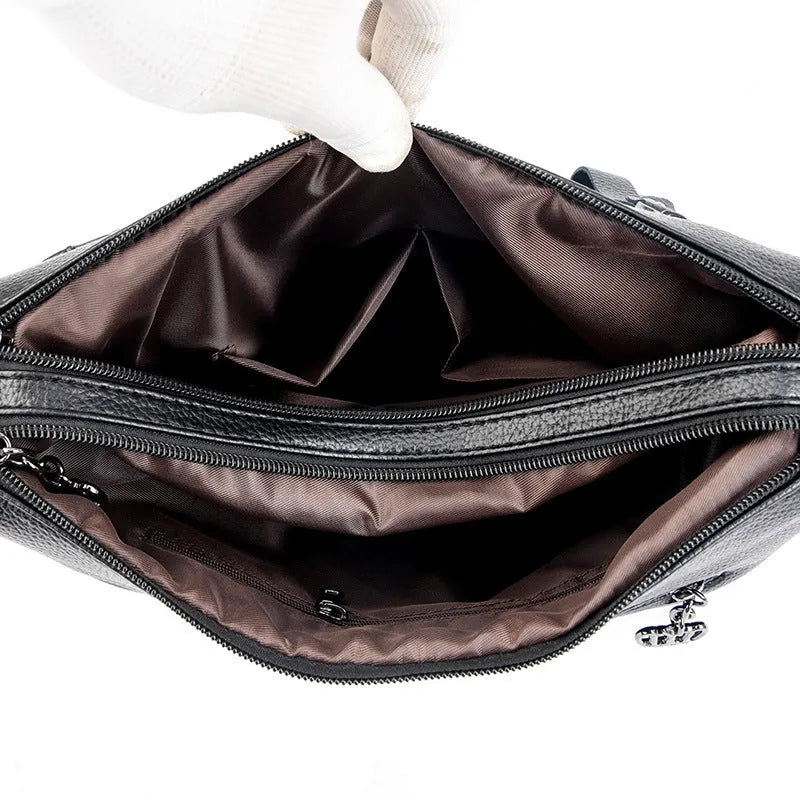 Genuine leather horizontal square messenger bag in black with contrast stitching and a front slit pocket.
