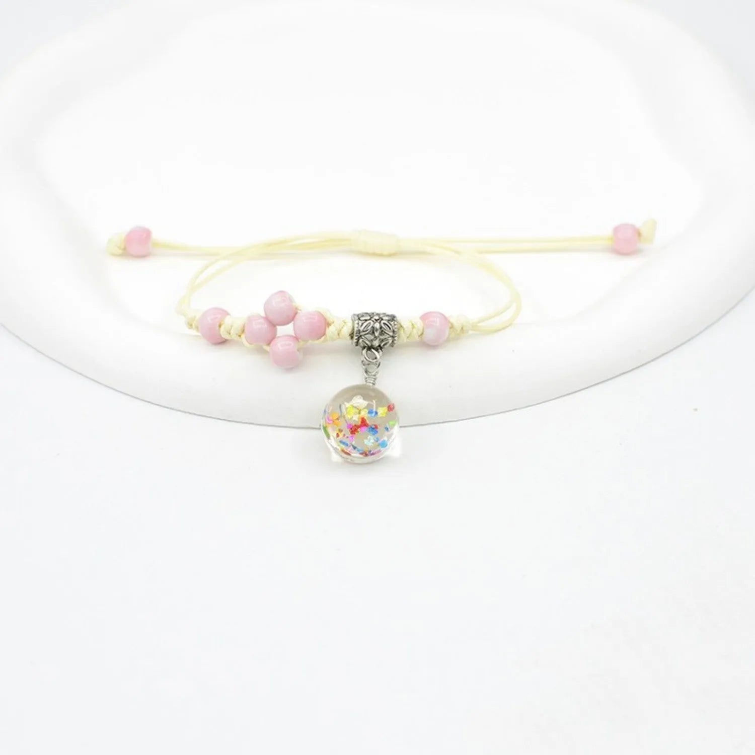 Close-up of a hand-woven glass bracelet with large beads containing real dried flowers and a lace design.