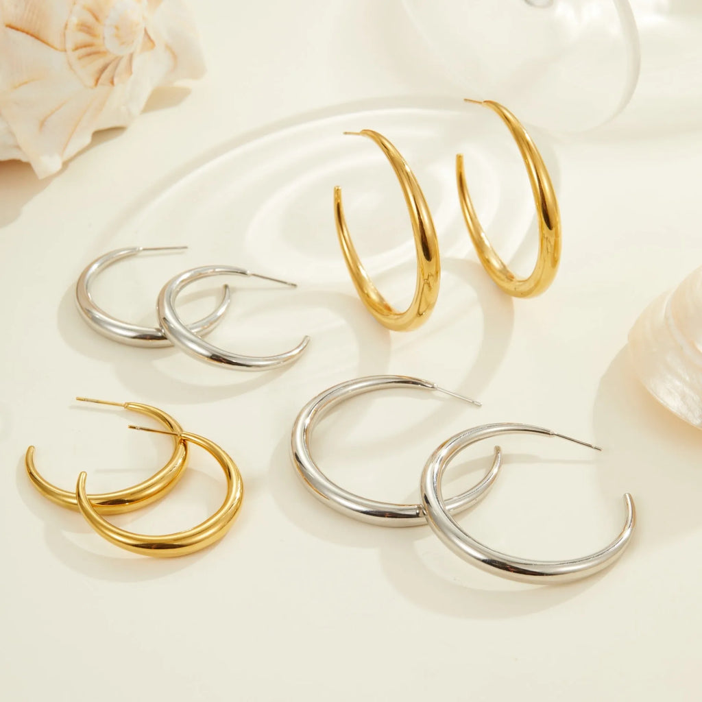 A pair of simple round titanium stainless steel hoop earrings shown in both gold and steel finishes.