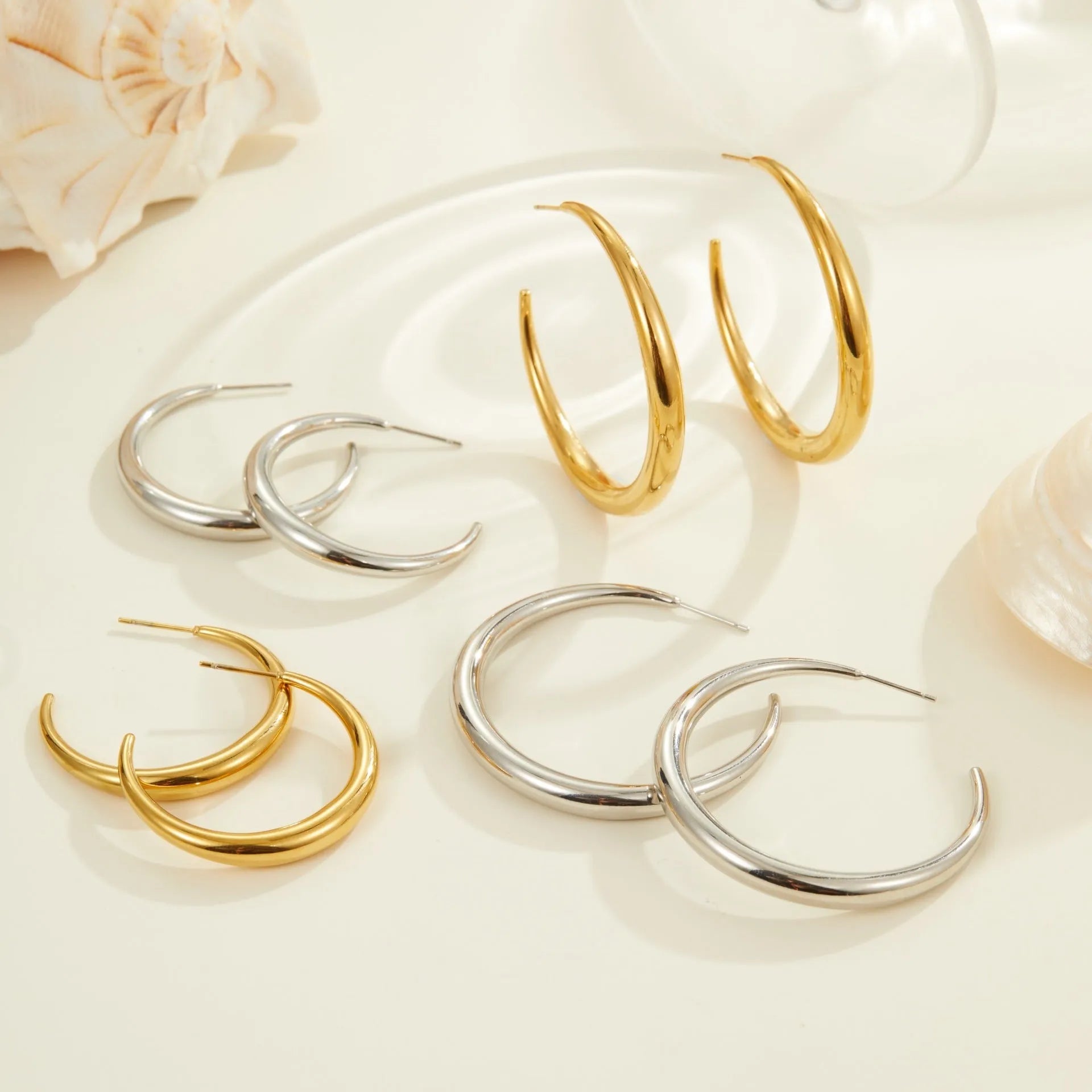 A pair of simple round titanium stainless steel hoop earrings shown in both gold and steel finishes.
