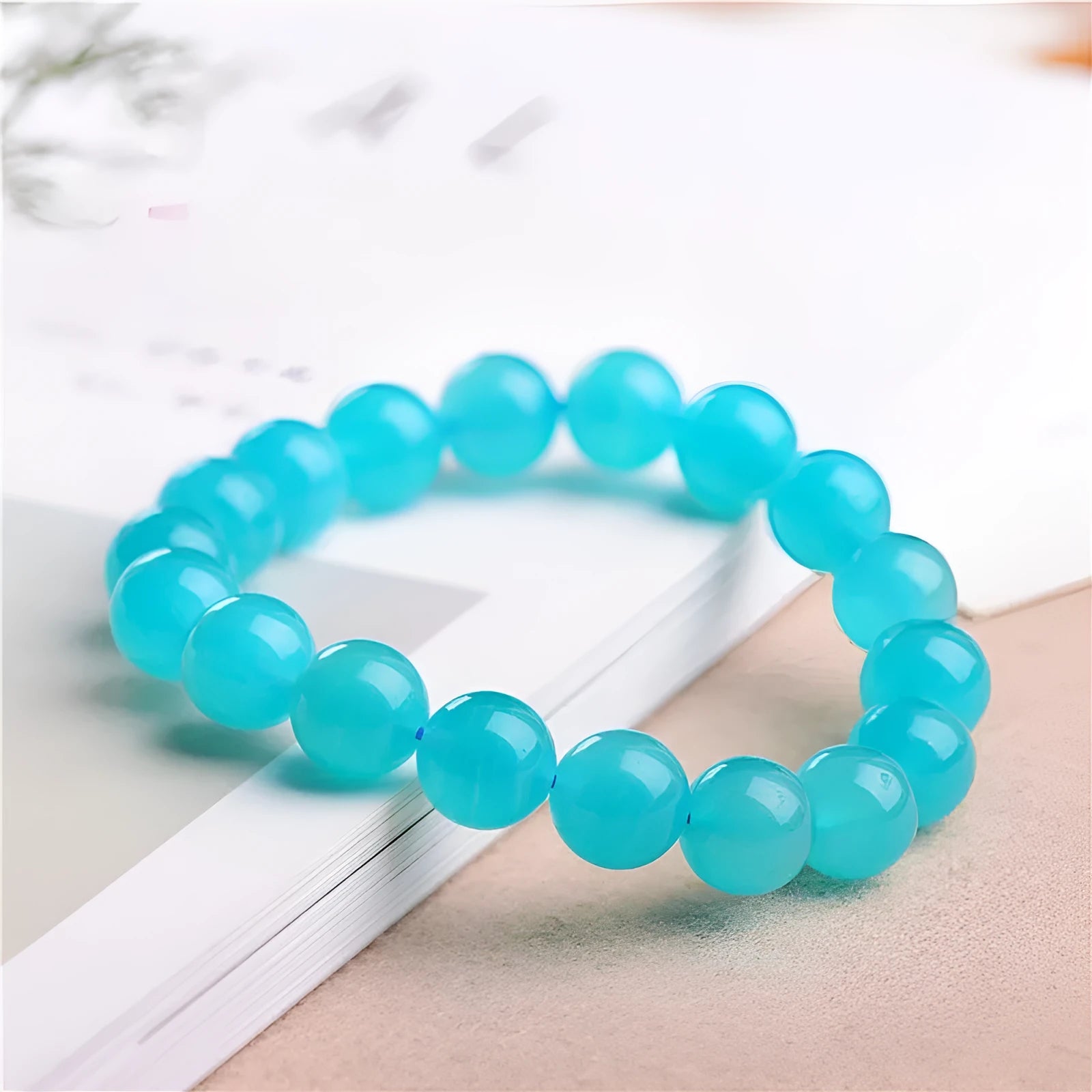 Natural blue-green Amazonite polished beads scattered on a surface, with a finished crystal bracelet.