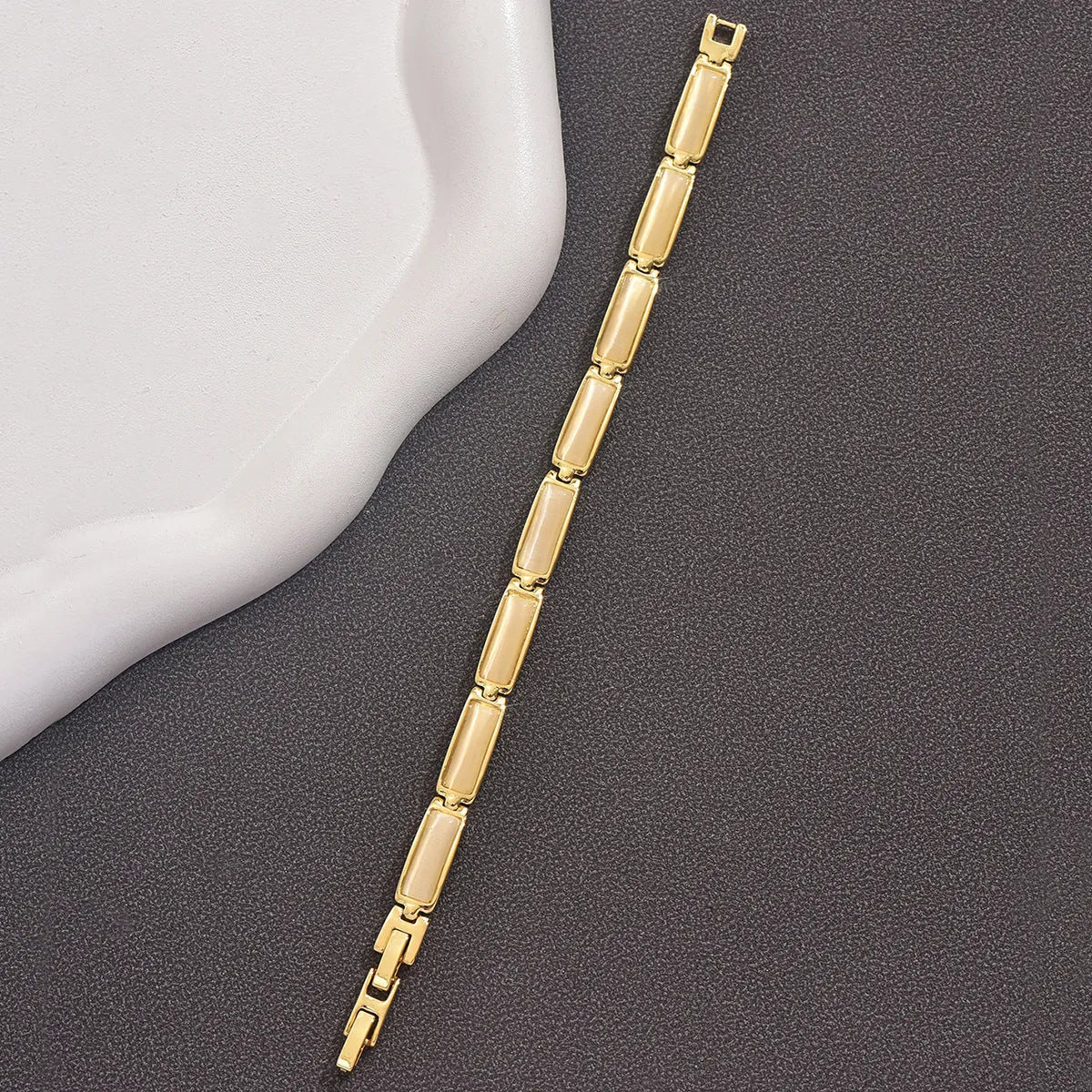 Women's geometric rose gold opal bracelet with quadrilateral shape and gemstone inlay on a plain background