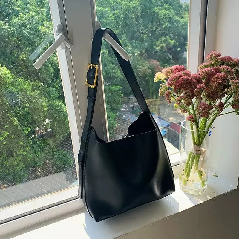 Two women's soft PU leather shoulder bags with swing threads, one black with ribbon and one brown with packet design