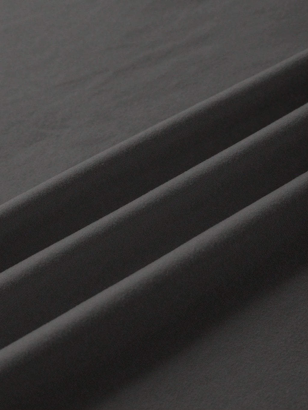 A loose-fitting black cotton T-shirt with short sleeves and a round neck on a hanger.