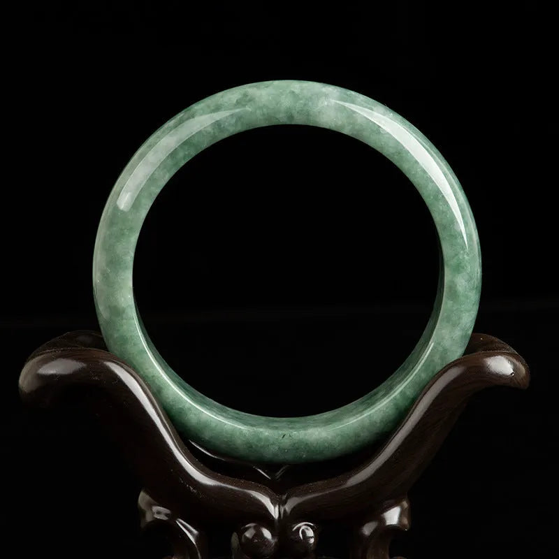 Natural deep pea green emerald stone bracelet on a wrist, showing its simple band design.