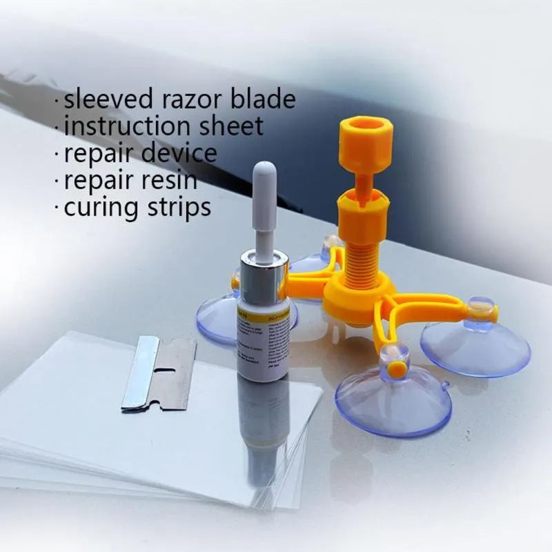 Windshield repair fluid kit with green resin, repair device, curing strips, and sleeved razor blade on a car windscreen