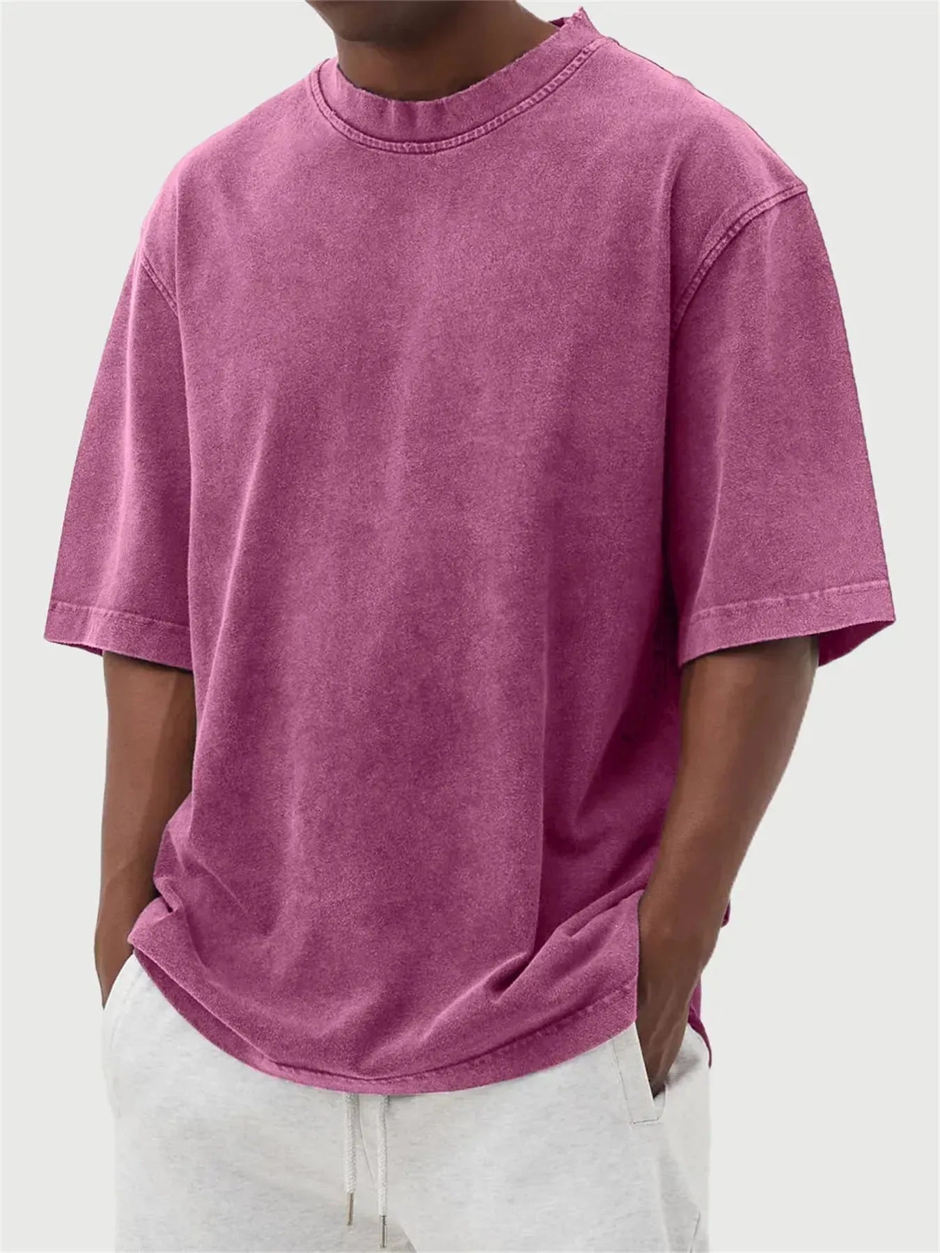 Man wearing a loose-fit, stone-washed polyester T-shirt in a solid colour with a distressed finish.