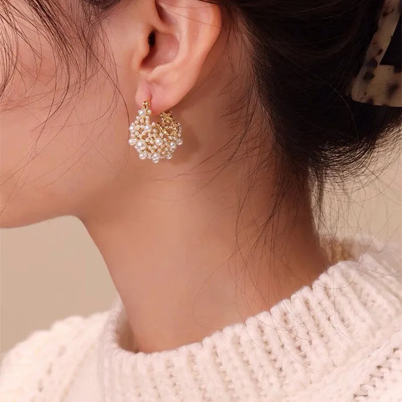 Gold-coloured copper flower basket earrings with small rice-shaped beads and pearl inlay detail.