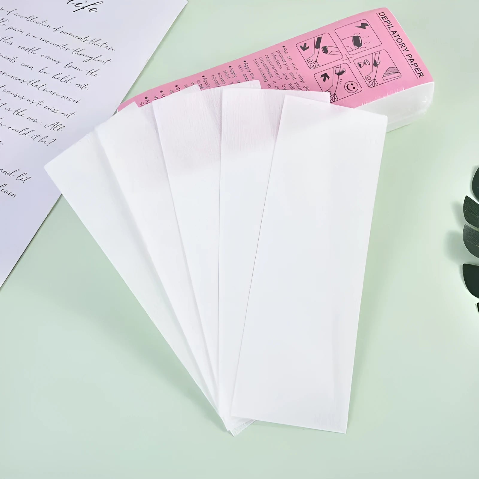 Pack of soft non-woven fabric hair removal wax paper strips on a pink background