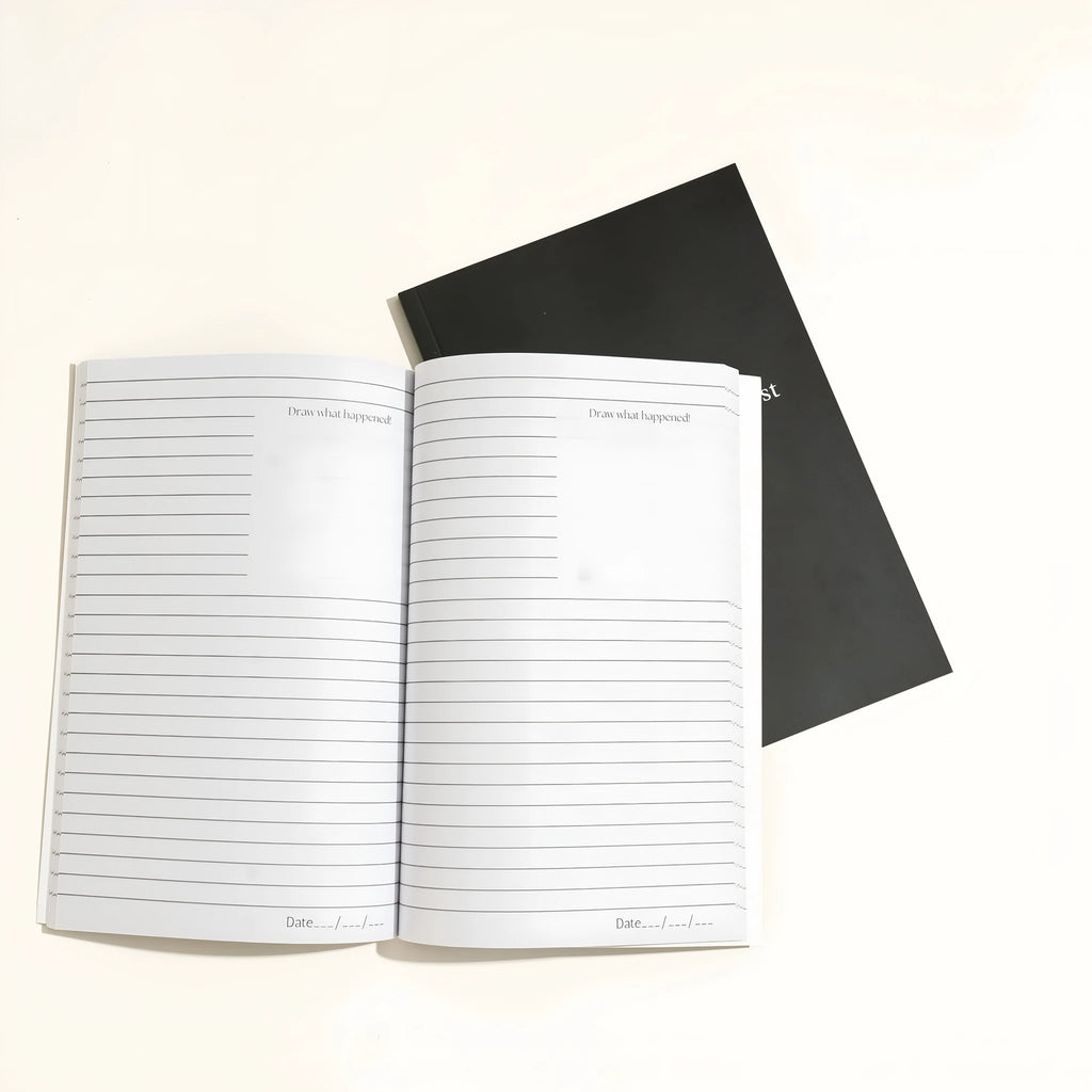 Black covered dream journal notebook open to show cream dot grid pages