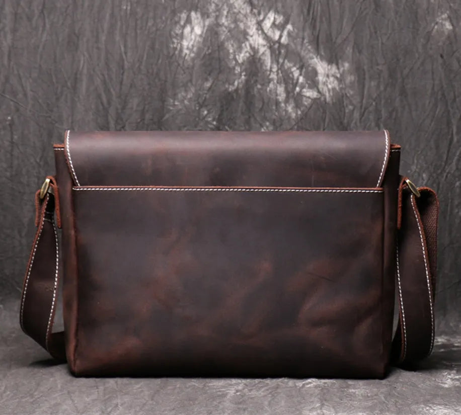 Men's vintage brown cowhide medium messenger bag showing front flap and long shoulder strap.